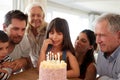 Three generation white family celebrating young girlÃ¯Â¿Â½s birthday with a cake and candles, close up